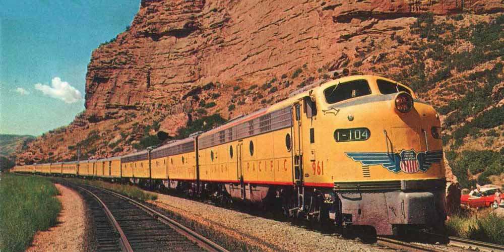 a vintage yellow union pacific train coming around a bend